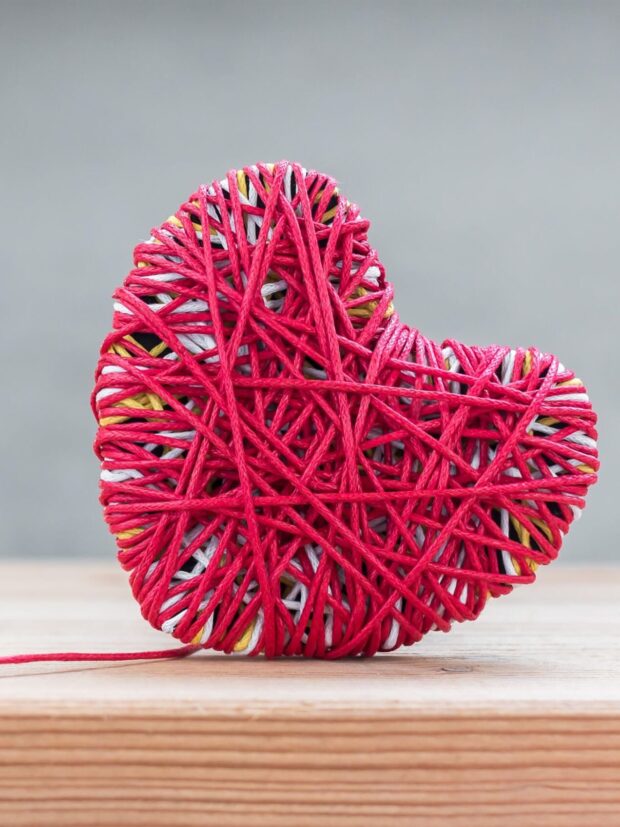 Read heart yarn on wood table over grunge cement background